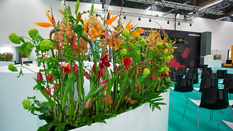 Pflanzen und Blumen schmücken einen Messestand